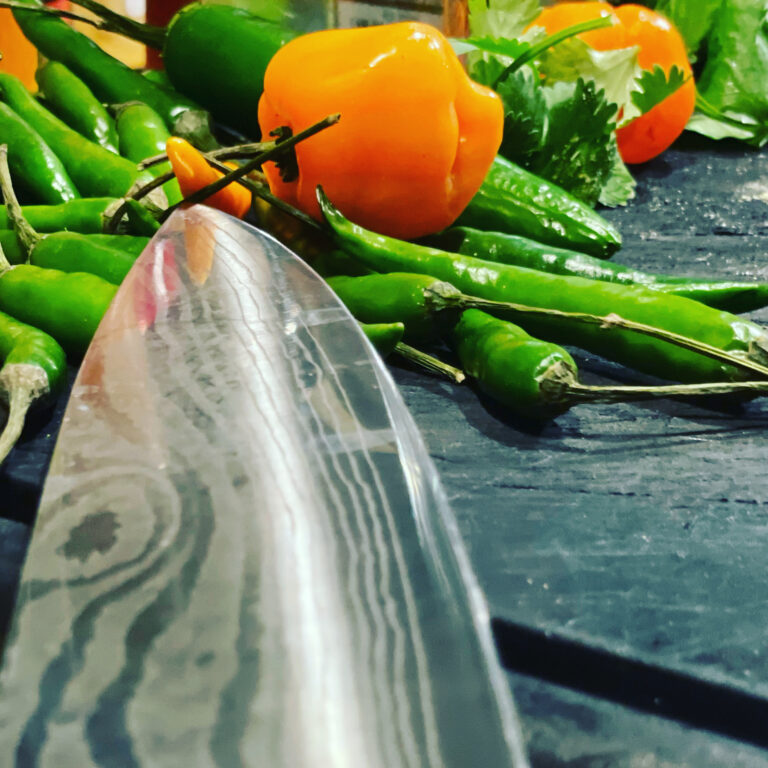 Peppers on a cutting board with a knife.